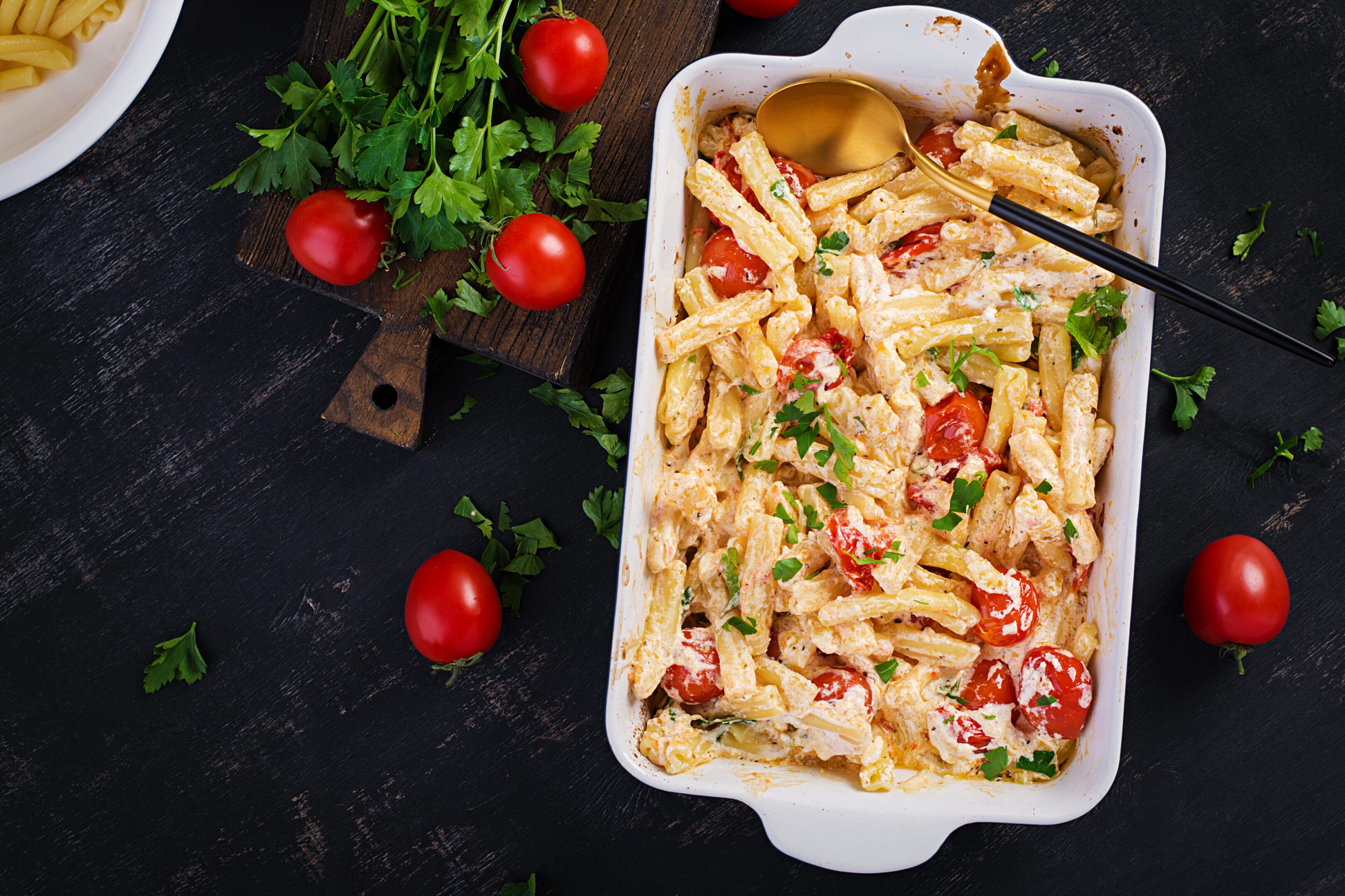 Fetapasta. Trending viral Feta bake pasta recipe made of cherry tomatoes, feta cheese, garlic and herbs in a casserole dish. Top view, above, copy space.