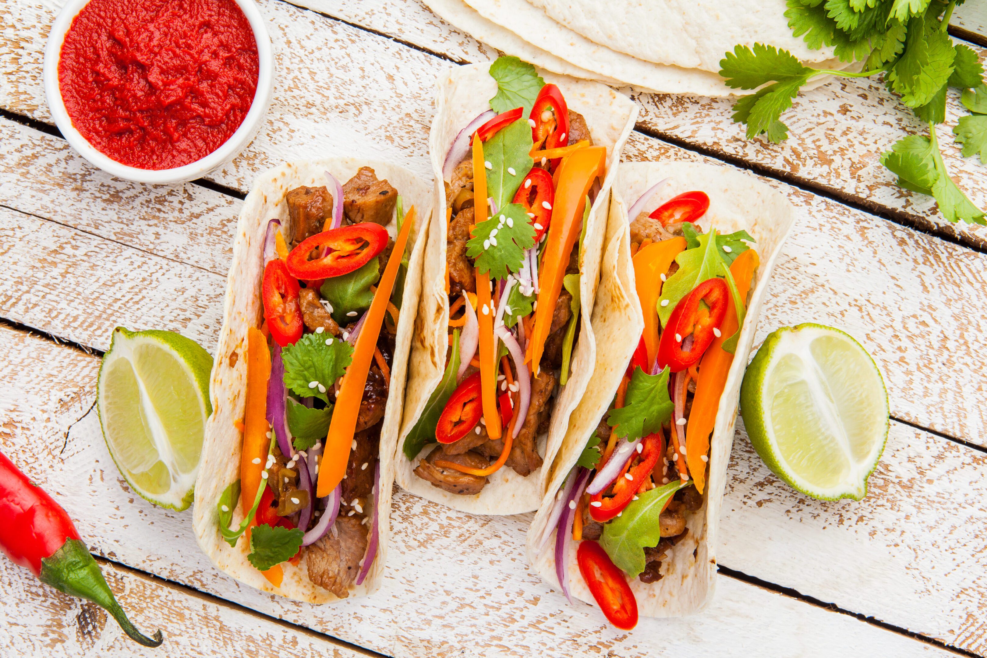 Three Mexican tacos with meat and vegetables. Top view.