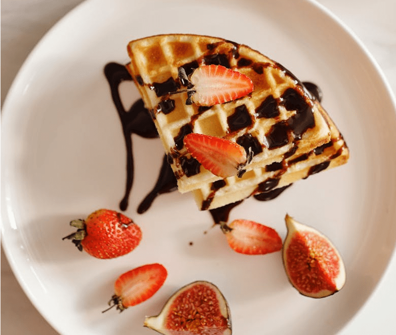 Waffles with strawberries, figs, and chocolate drizzle.