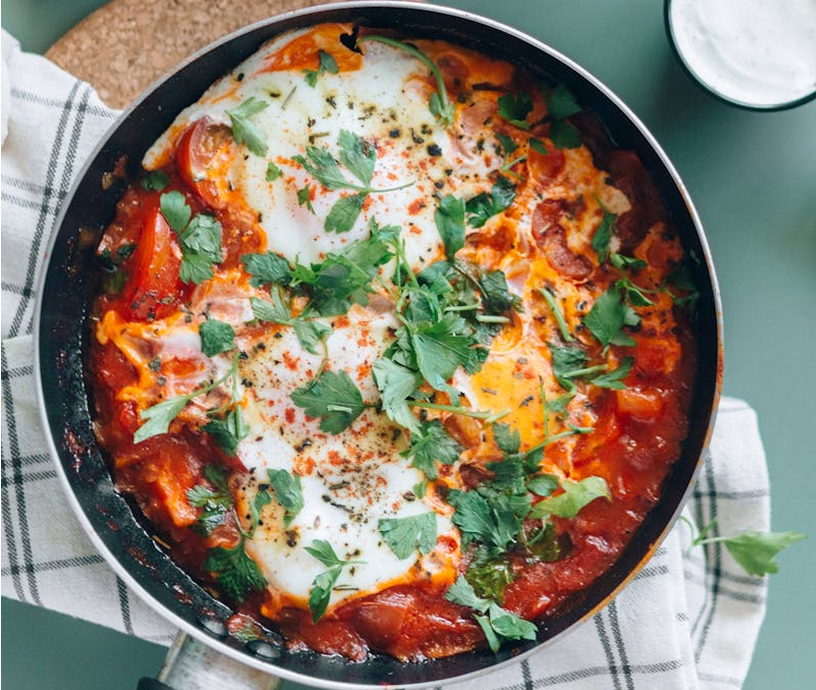 Shakshuka in a skillet with herbs.