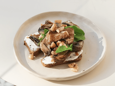Open-faced sandwich with mushrooms and greens.