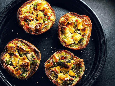 Four mini pizzas on a black plate.