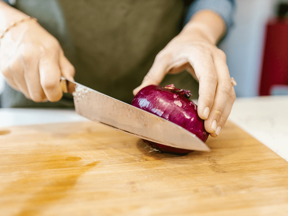 Chopping a red onion on wooden board.