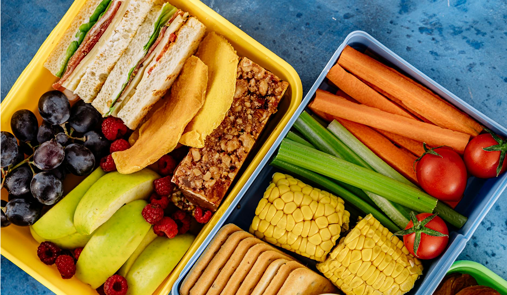Colorful lunchboxes with fruits and vegetables.