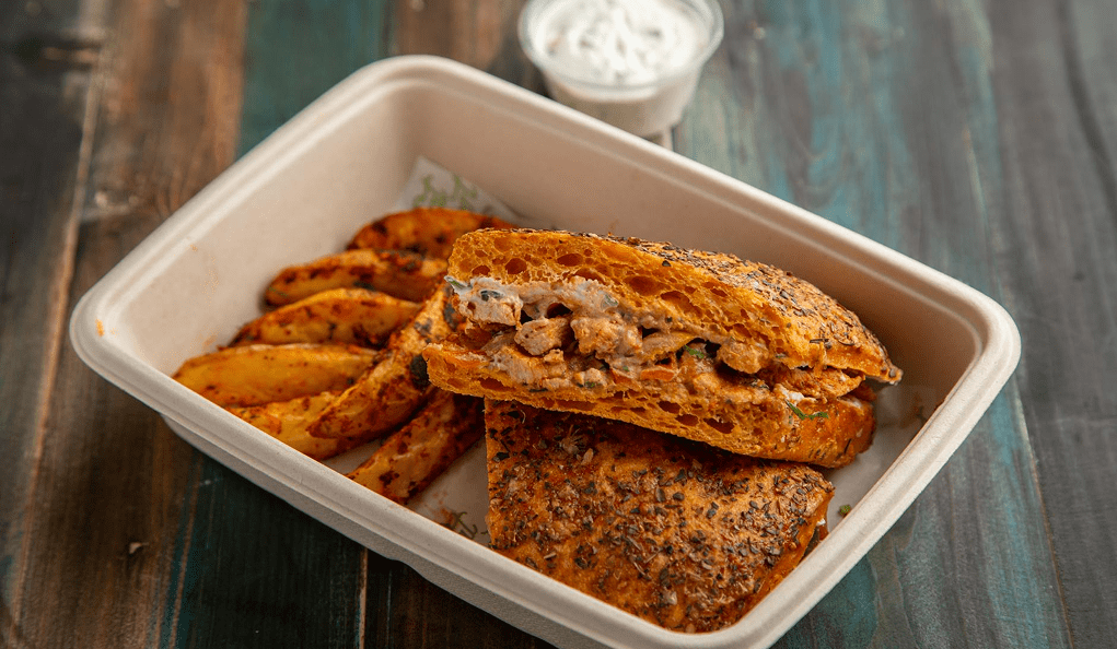 Sandwich with potato wedges in a container.
