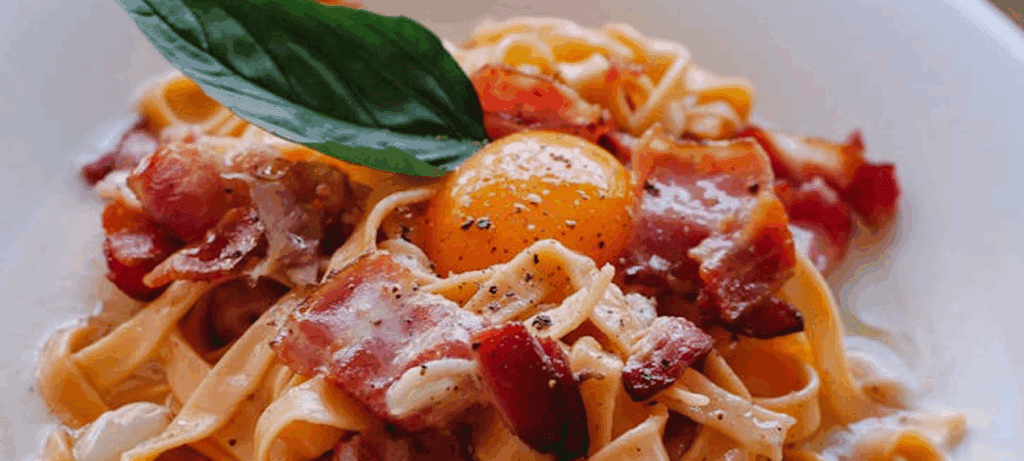 Pasta with bacon, egg yolk, and basil.