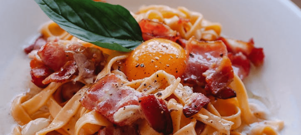 Pasta with bacon, egg yolk, and basil.