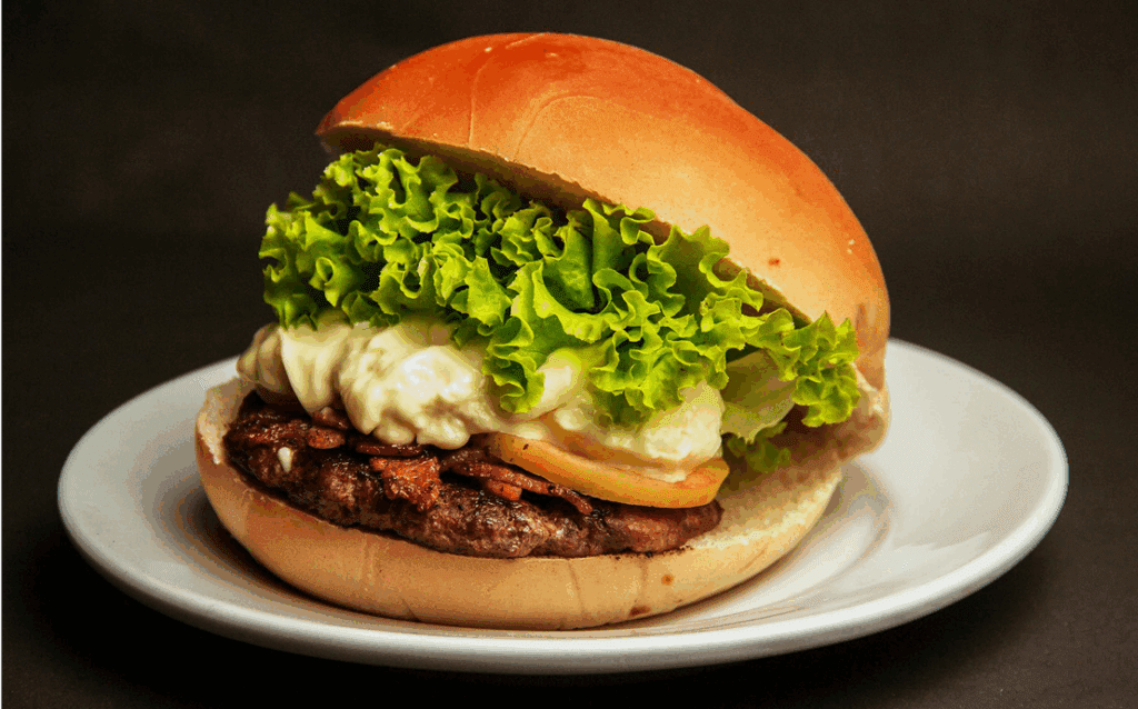 Burger with lettuce and mayonnaise on plate.